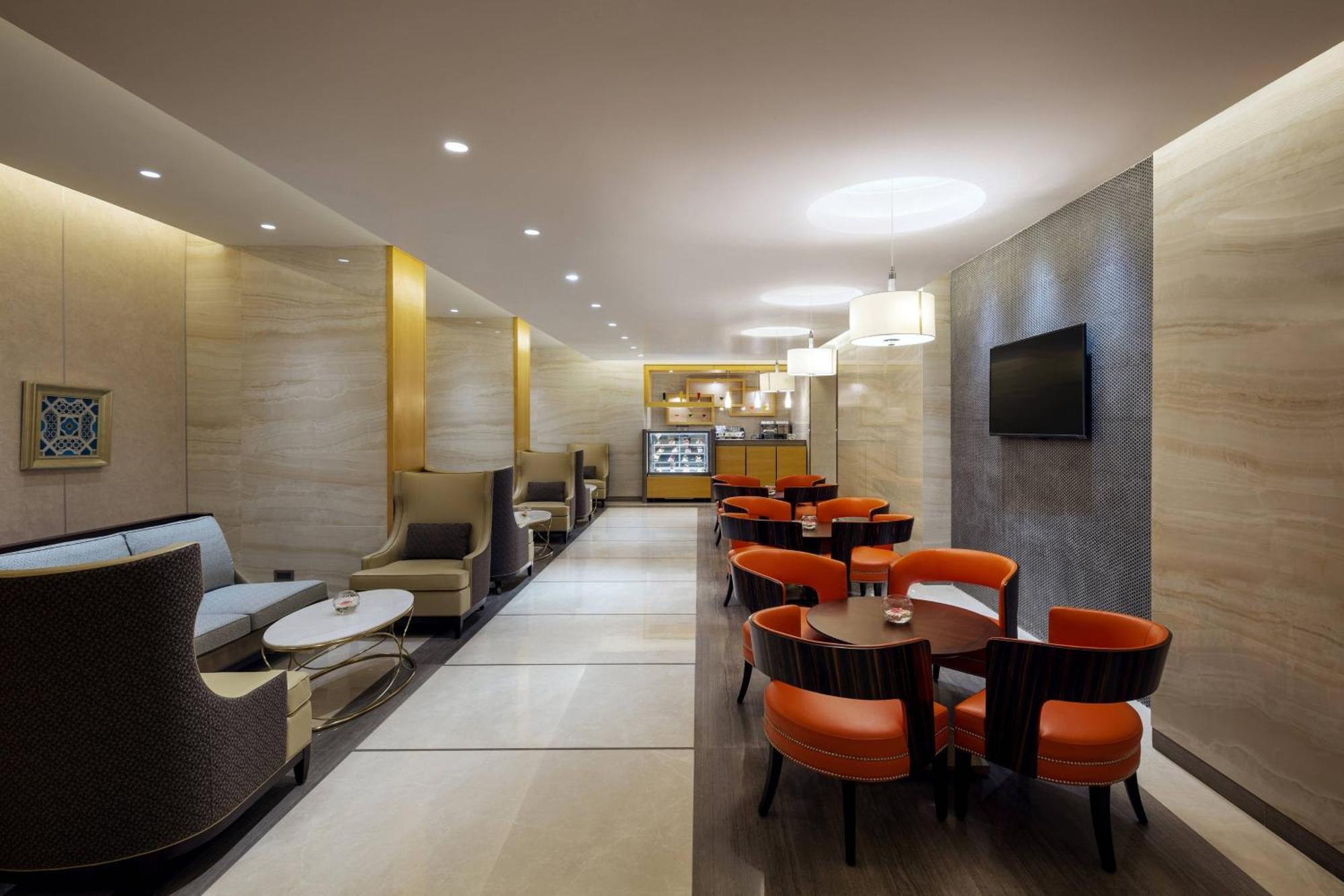 Sheraton Makkah Jabal Al Kaaba Hotel La Meca Exterior foto The photo depicts a modern and elegant lounge or café area. The interior features soft, warm lighting and a combination of neutral and bold color schemes. On the left side, there are comfortable seating arrangements with light-colored sofas and chair